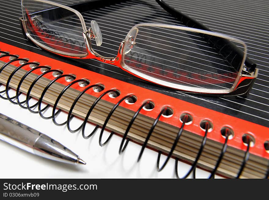 Black and red colored ring binder, glasses and ball point. Black and red colored ring binder, glasses and ball point