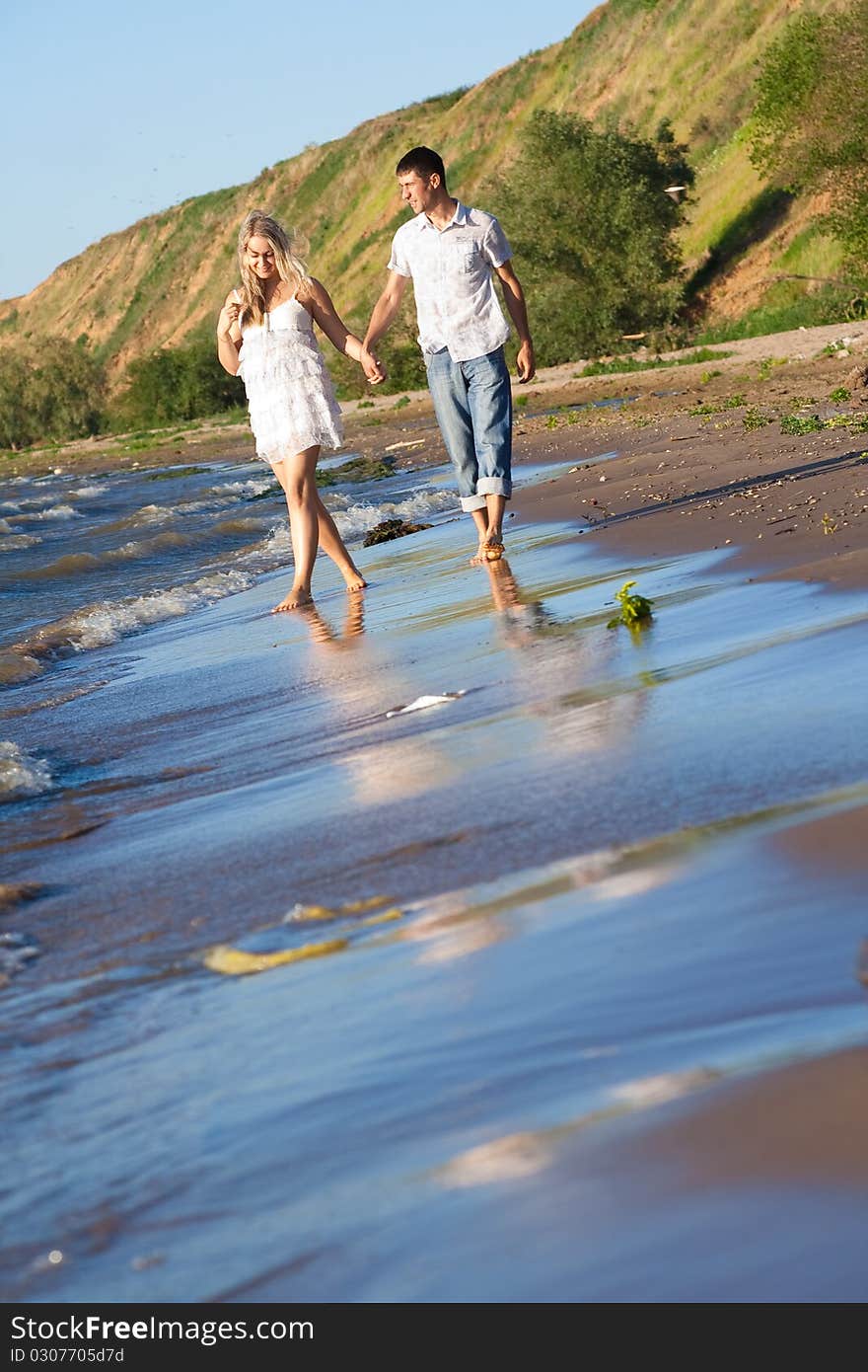 The loving couple walks on river bank. The loving couple walks on river bank