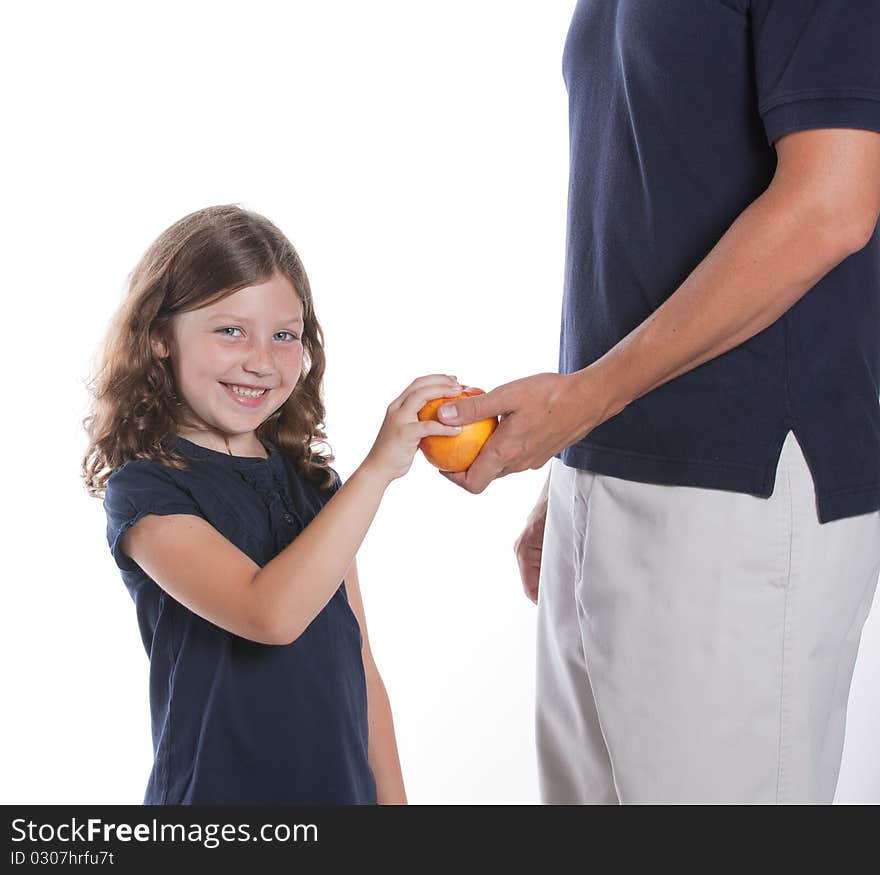 A cute little girl smiles as her dad gives her an apple for a snack. A cute little girl smiles as her dad gives her an apple for a snack