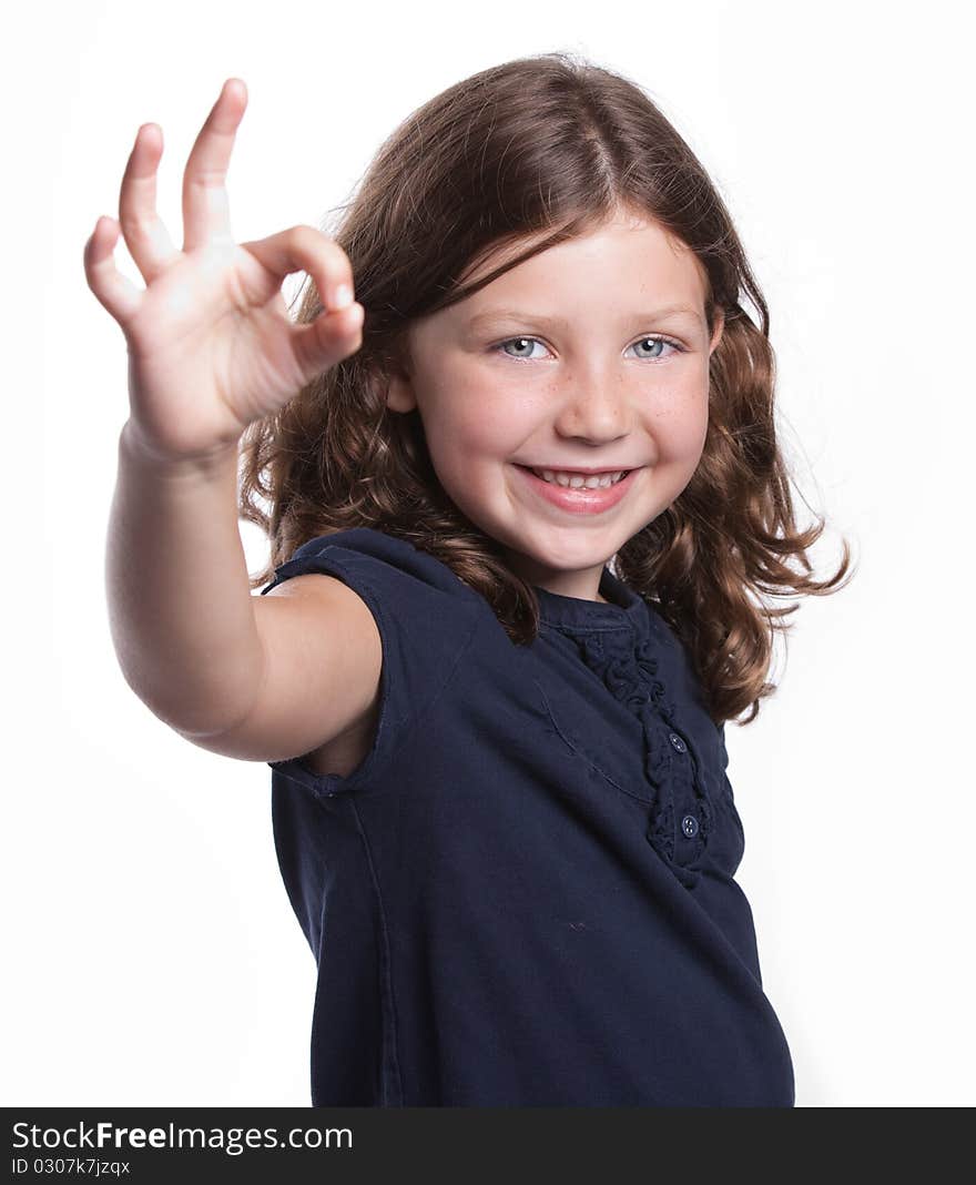 A cute little girl with curly hair and freckles gives an O.K. sign while smiling. A cute little girl with curly hair and freckles gives an O.K. sign while smiling