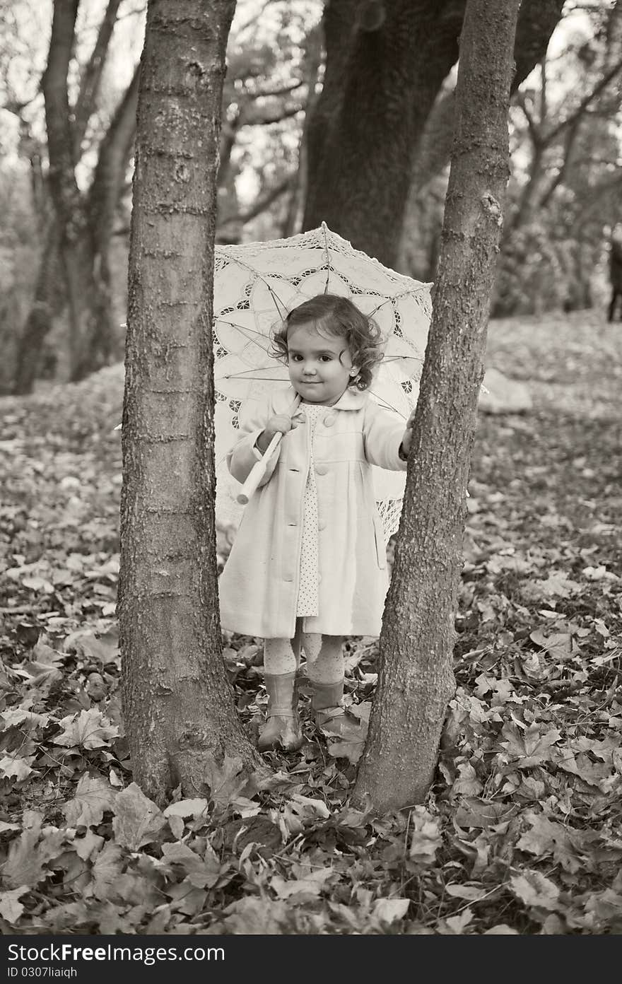 Little girl with umbrella in the park in autumn