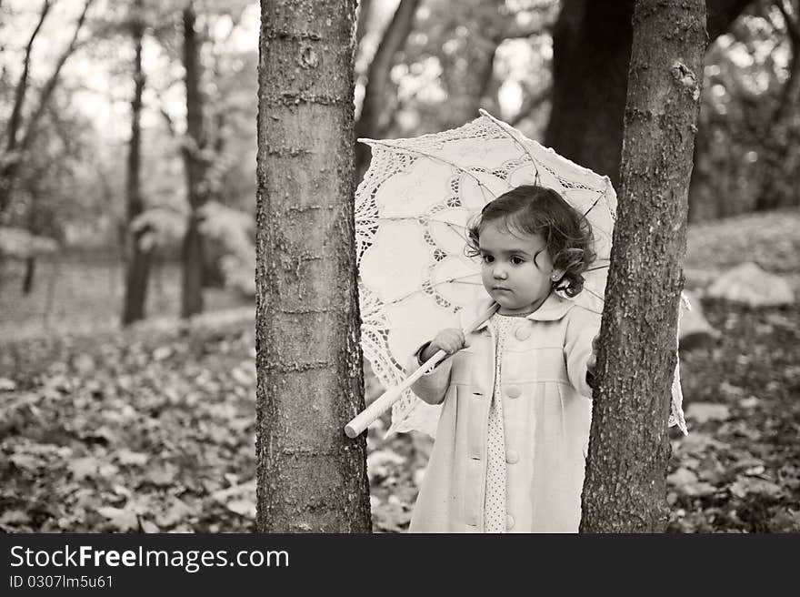 Little girl with umbrella in the park in autumn