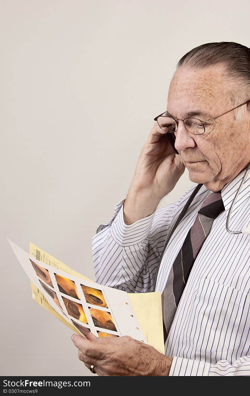 Doctor talks on cell phone as he looks at results of colon test. Doctor talks on cell phone as he looks at results of colon test.