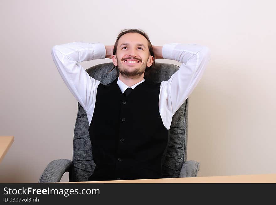 A business man in his office rests in the chair.