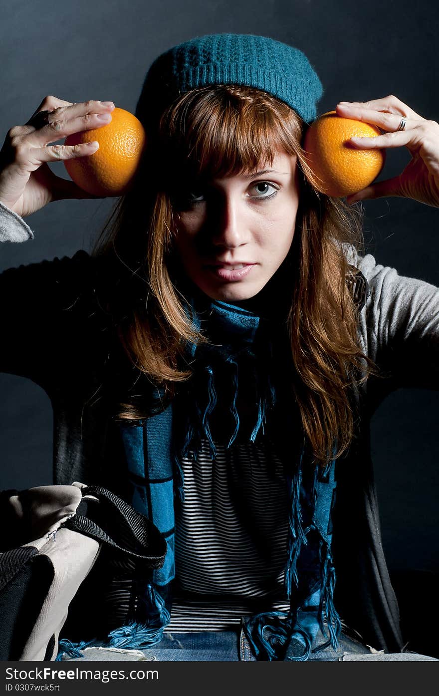 Beautiful girl with scarf and hat and oranges