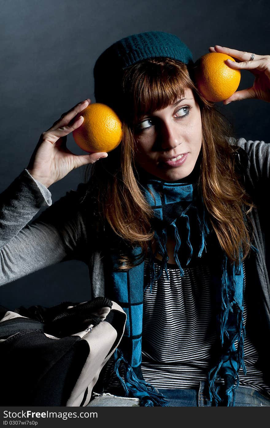 Beautiful girl with scarf and hat and oranges