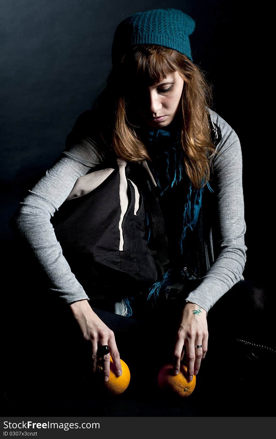 Beautiful girl with scarf and hat and oranges on a black background