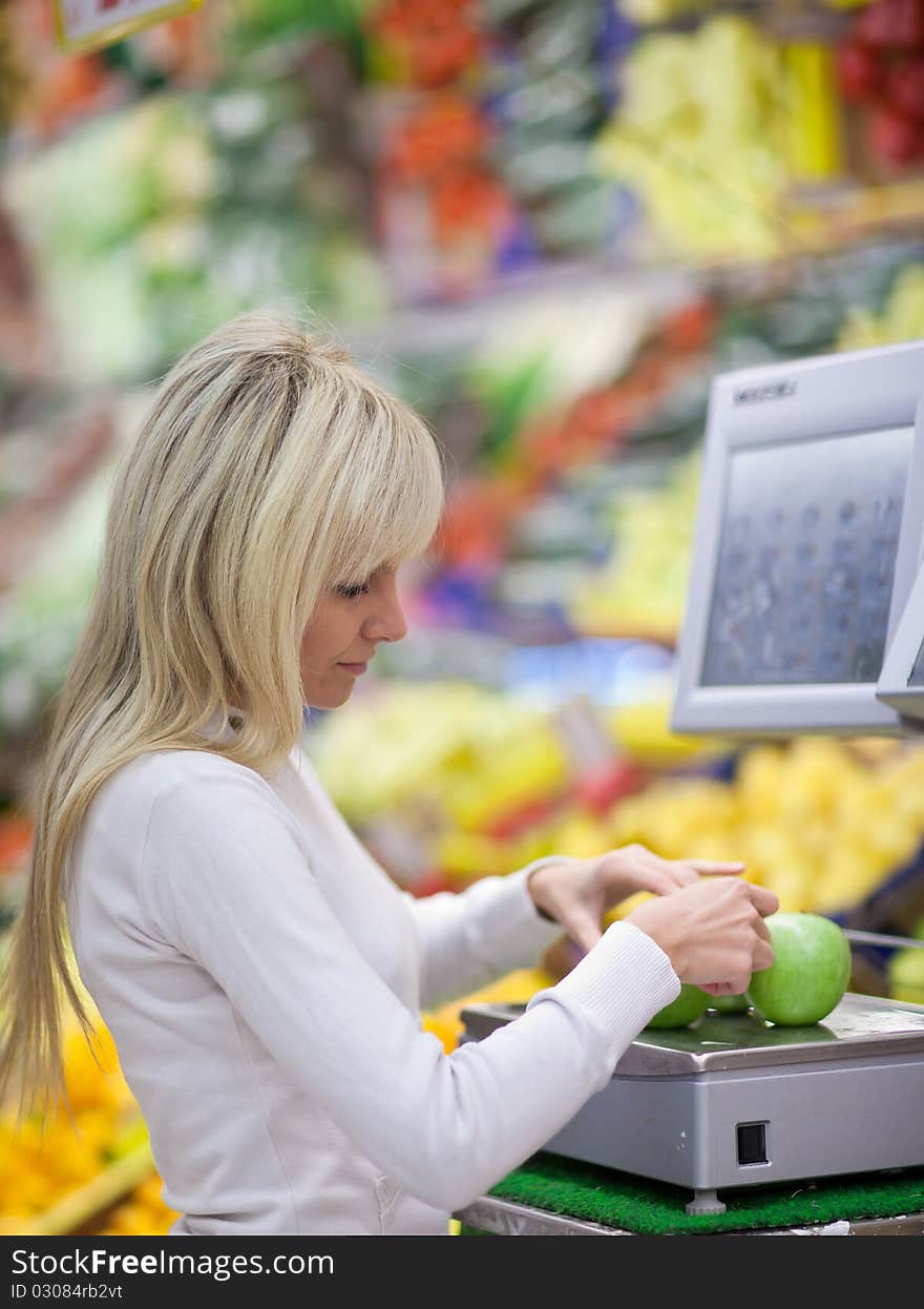 Beautiful young woman shopping for fruits and vegetables in produce department of a grocery store/supermarket