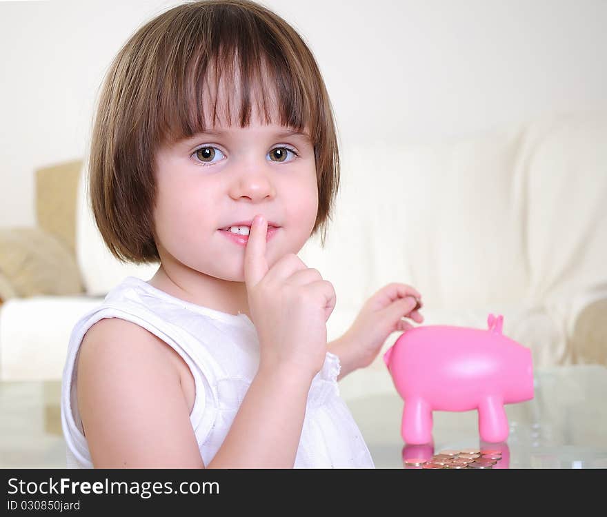 A little girl hides her money in the pig piggy bank.