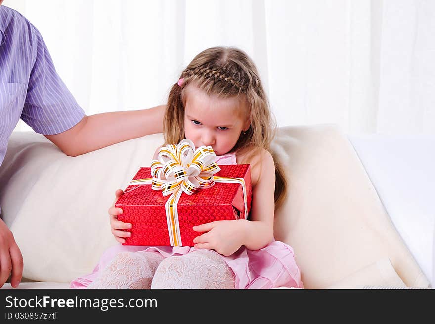 The father gives his young daughter in a red gift box with a white ribbon.