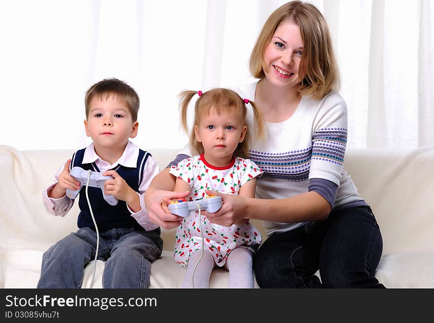 Little brother and sister and his mother played video games while sitting on the couch