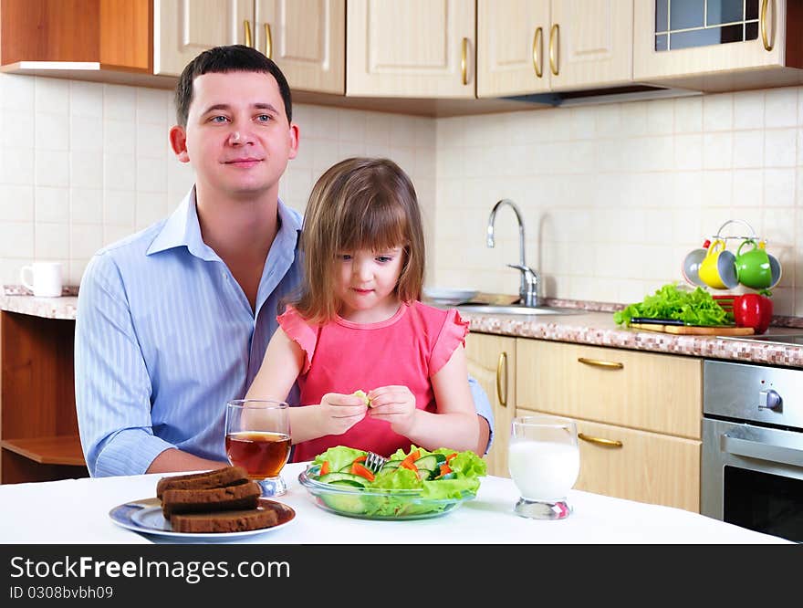 Father and his young daughter eat breakfast together in his kitchen.