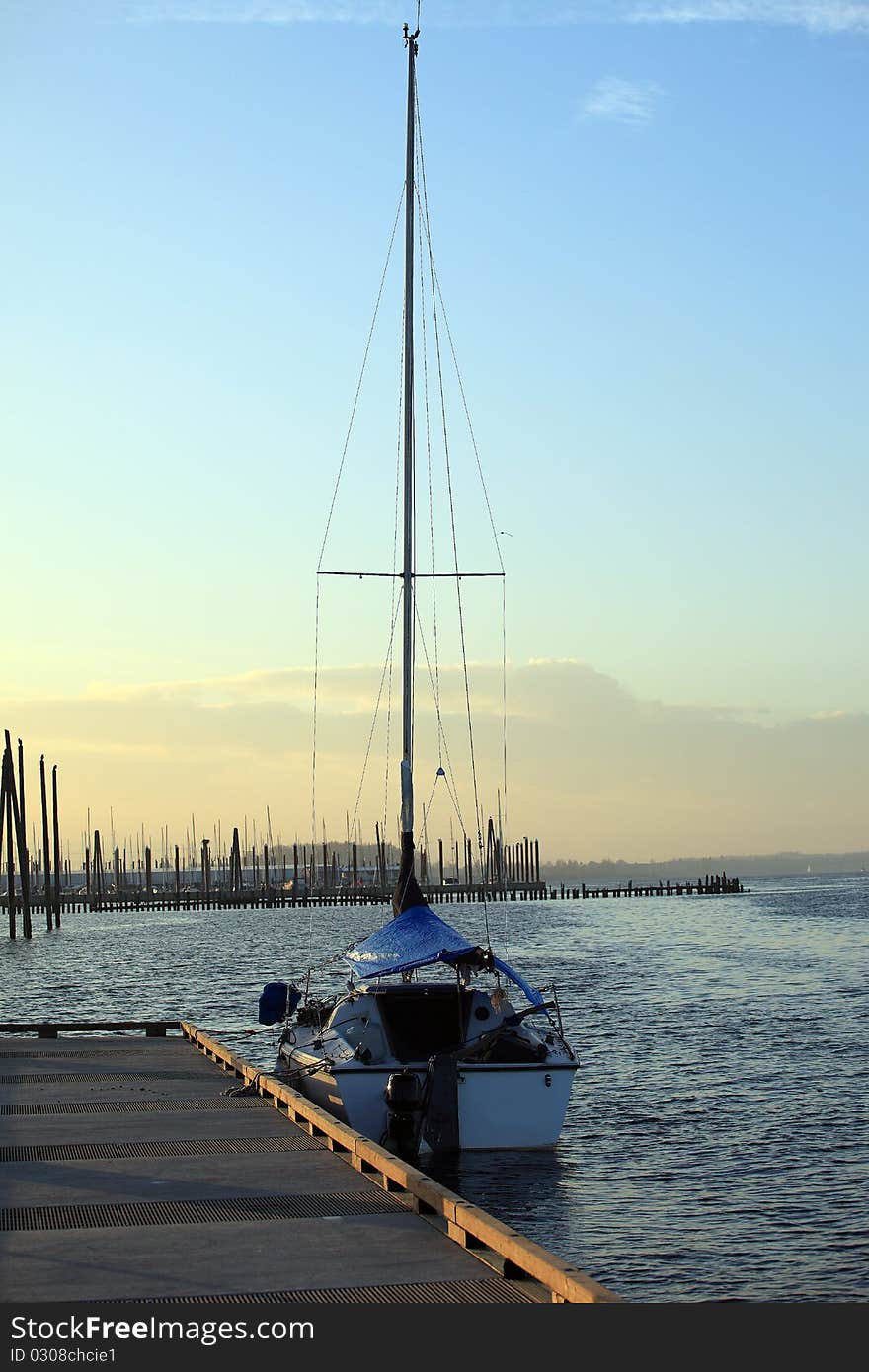 A sailboat in a river at sunset. A sailboat in a river at sunset.