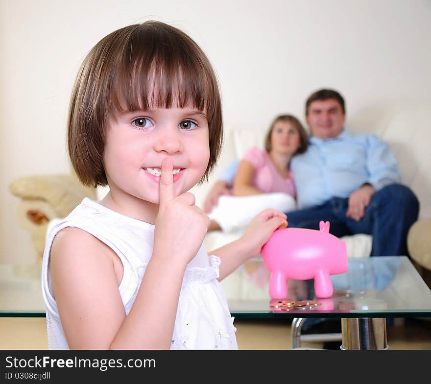 A little girl hides her money in the pig piggy bank.