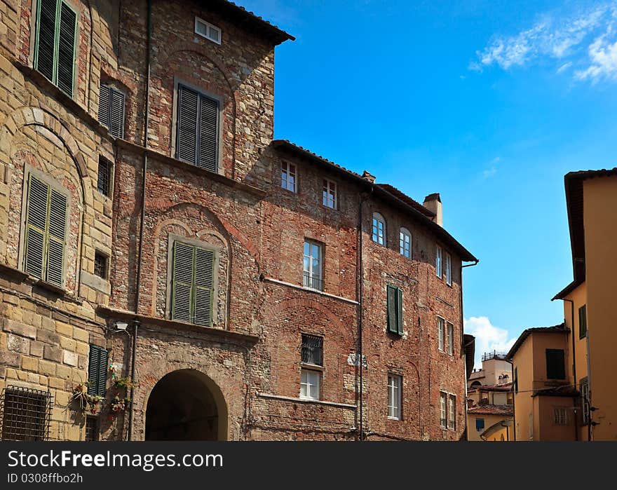 Residential apartment buildings in Lucca against a slightly cloudy sky.