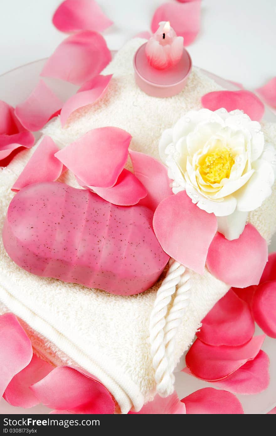 Pink hand made soap and pink rose petals on a white towel. Pink hand made soap and pink rose petals on a white towel