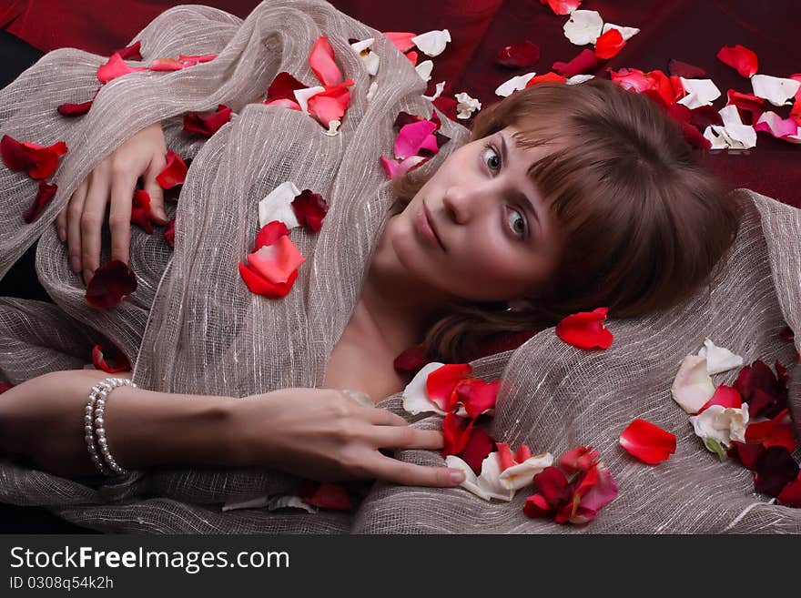 A young girl is in the petals of roses