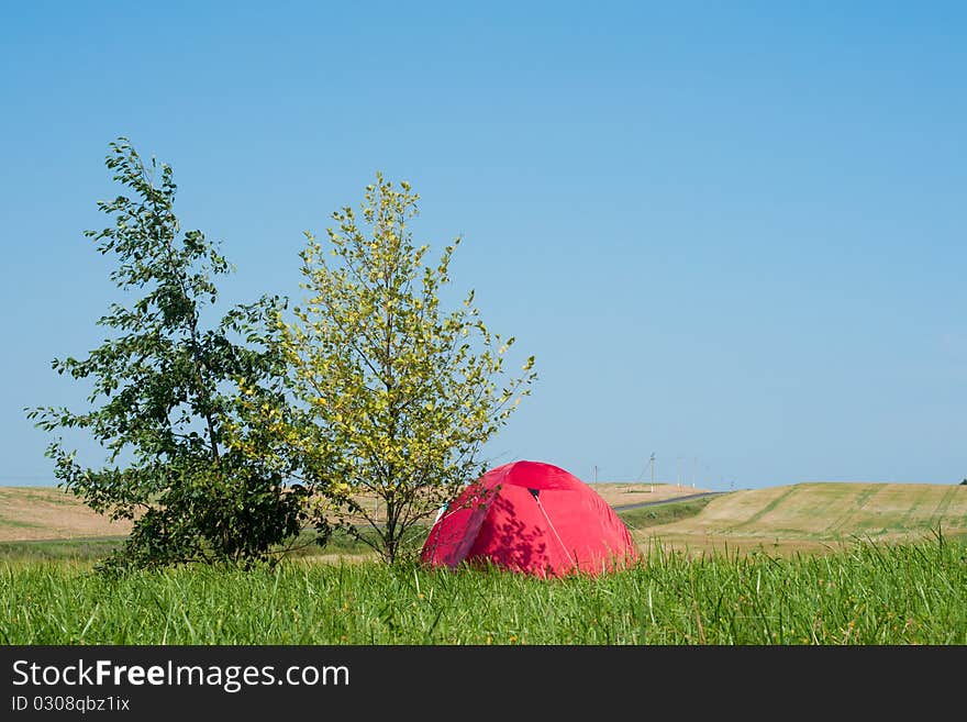 Tourist tent in the field with road and hills