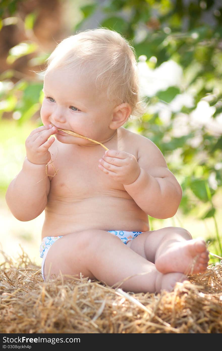 Baby girl sitting on straw.