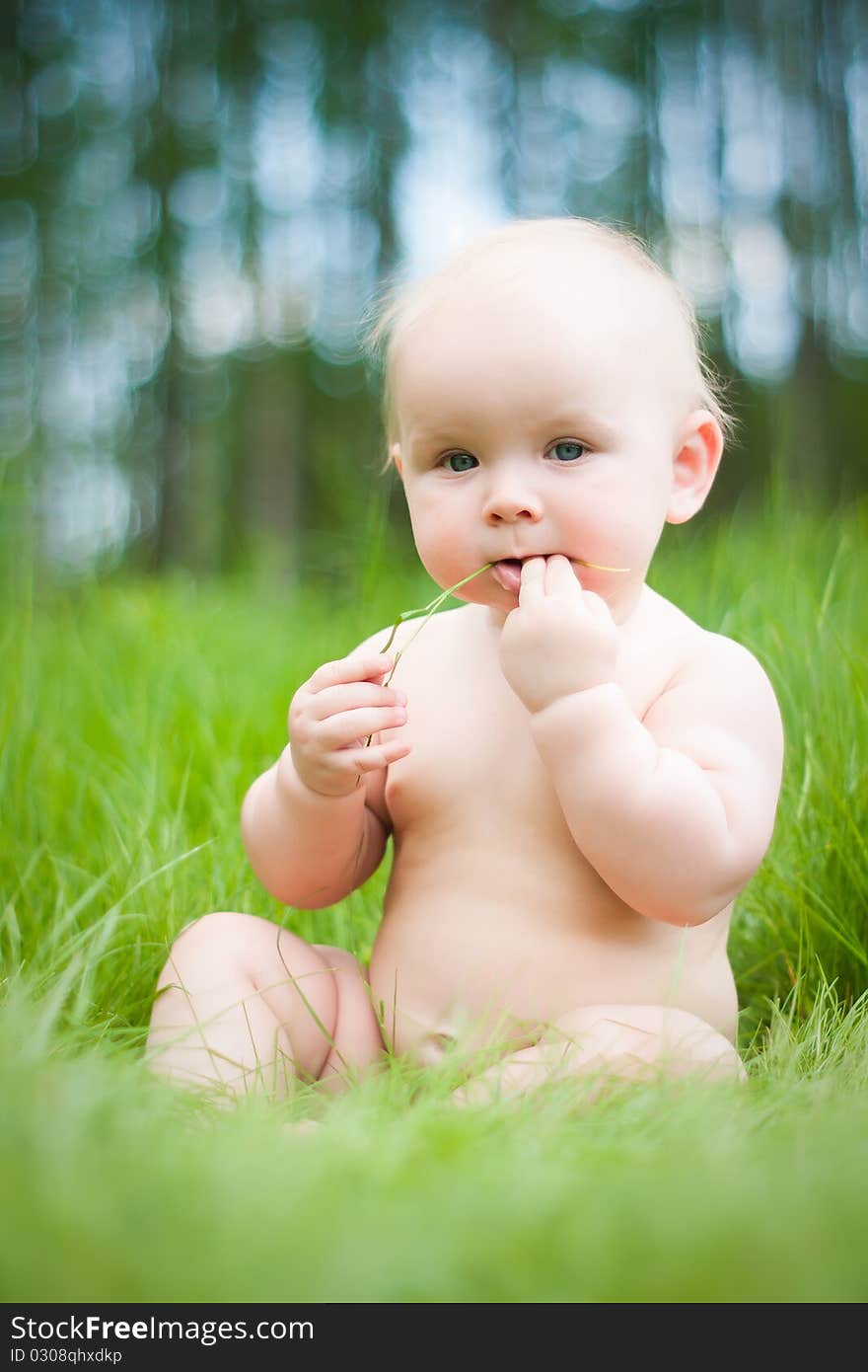 Baby sitting on green grass.