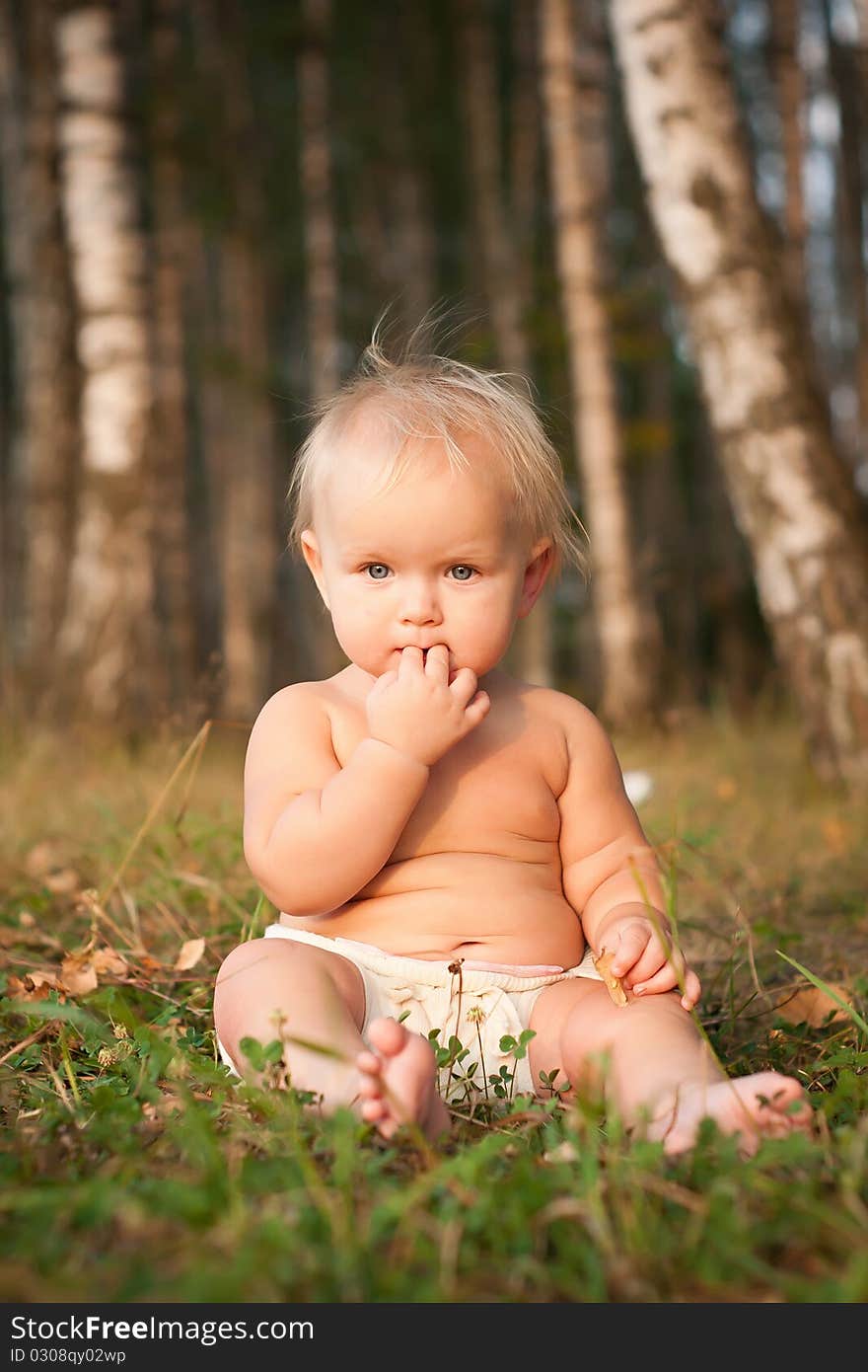 Girl sitting on green grass near forest