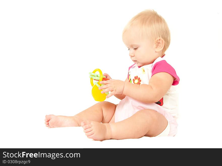 Happy cute baby girl (10 months) sitting on bed and playing with berry toy.