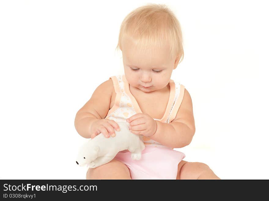 Happy cute baby girl (10 months) sitting on bed and playing with polar bear soft toy. Happy cute baby girl (10 months) sitting on bed and playing with polar bear soft toy