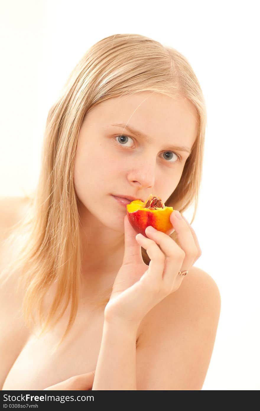 Beautiful young girl eating a peach on white