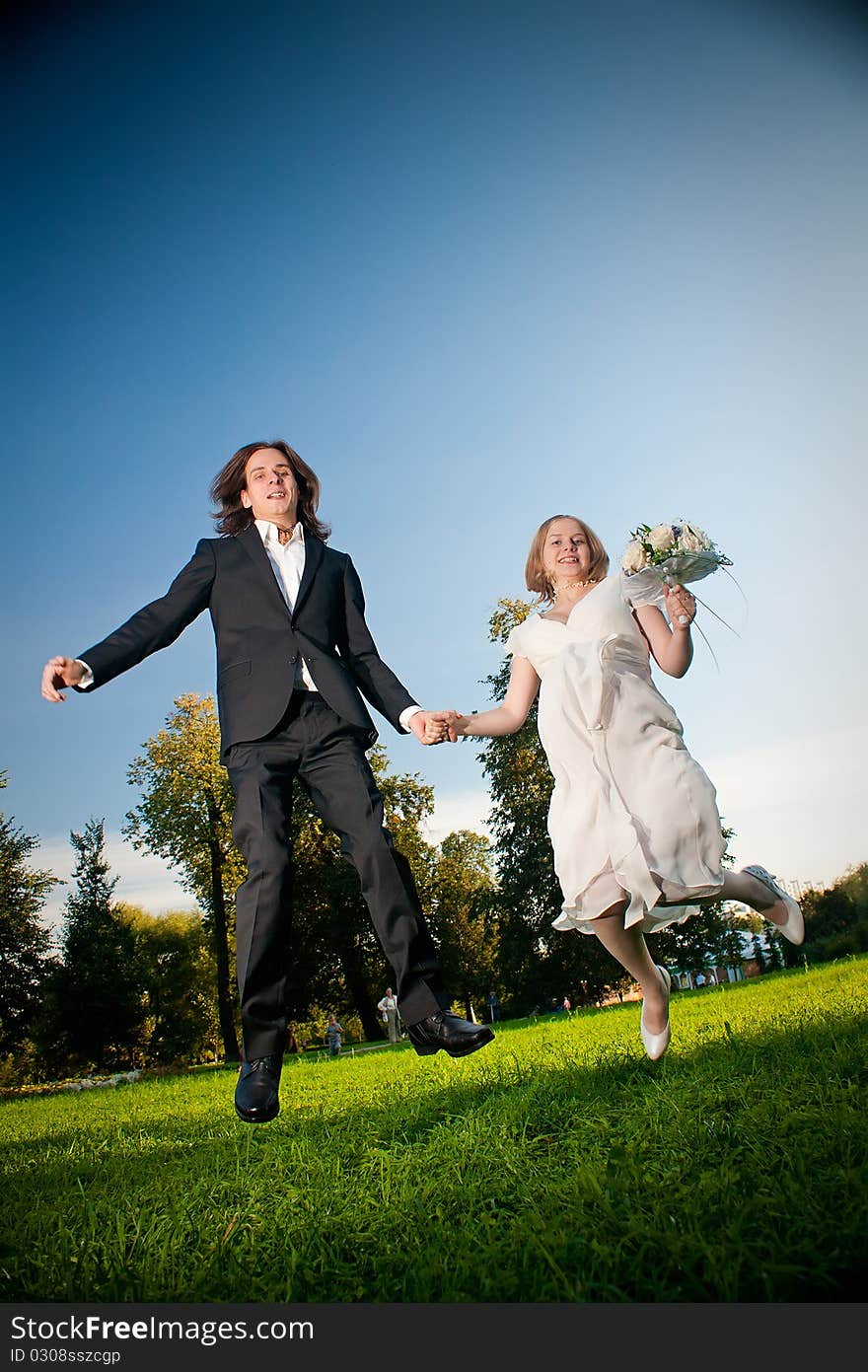 Young wedding lovely couple jump in park with flowers