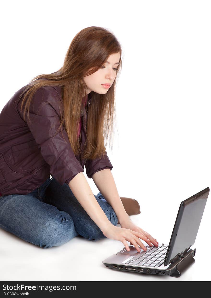 Girl with laptop is sitting on a floor. Isolated on white