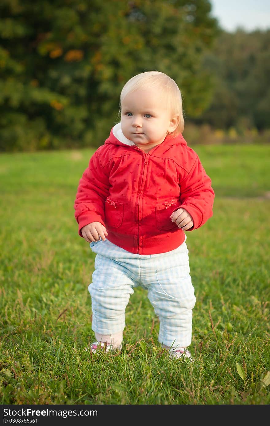 Young cheerful baby walking on the grass in park