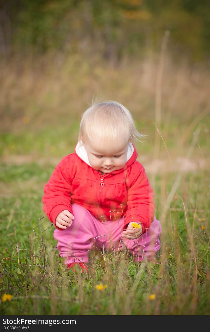 Young adorable baby sit near yellow flower in park