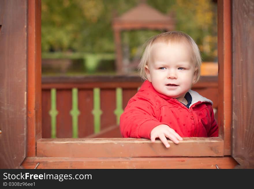 Young cheerful girl look through the window in house on playground