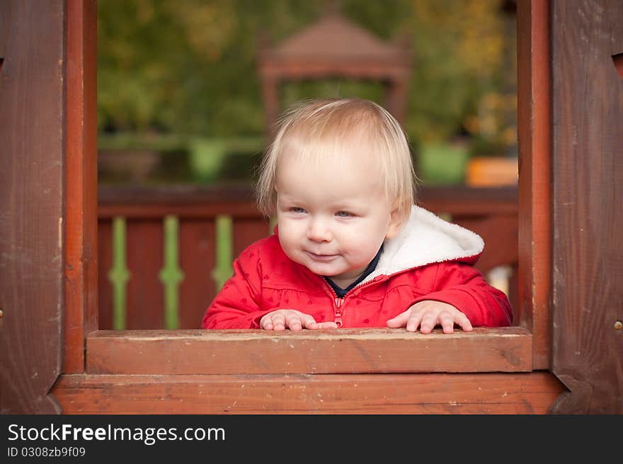 Young cheerful girl look through the window in house on playground