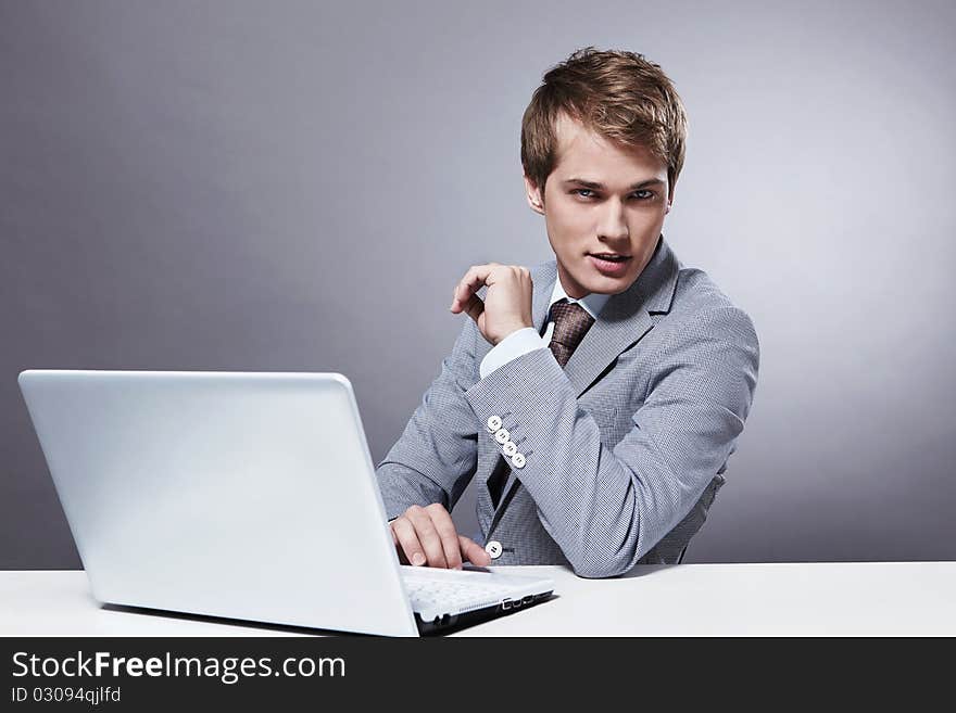 A young businessman at the table with a laptop. A young businessman at the table with a laptop