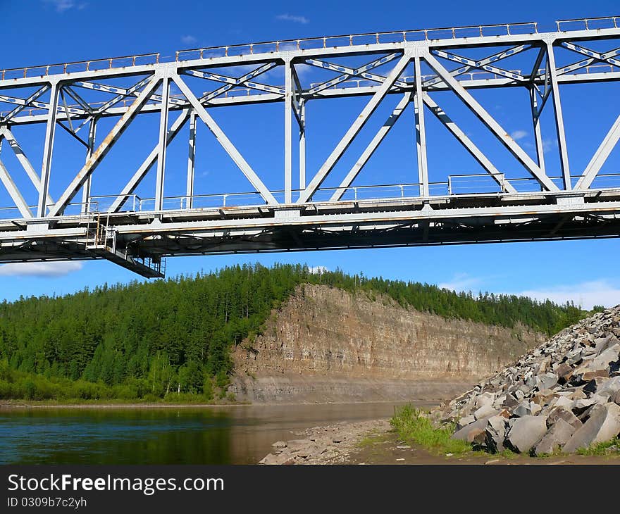 Rocky river bank and railway bridge. Landscape orientation.