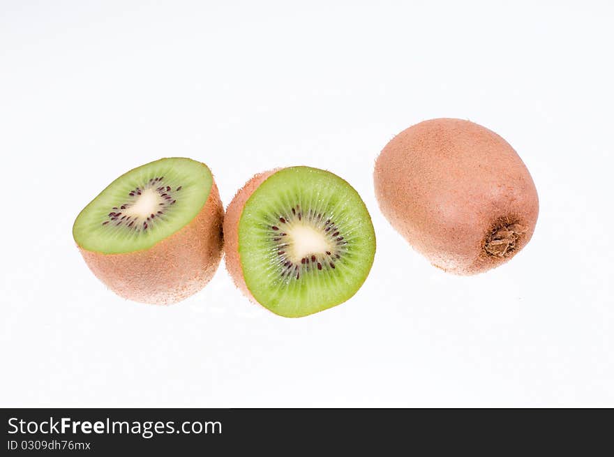 Two kiwi fruit on white background. One of the fruit is cut into two parts. Two kiwi fruit on white background. One of the fruit is cut into two parts.