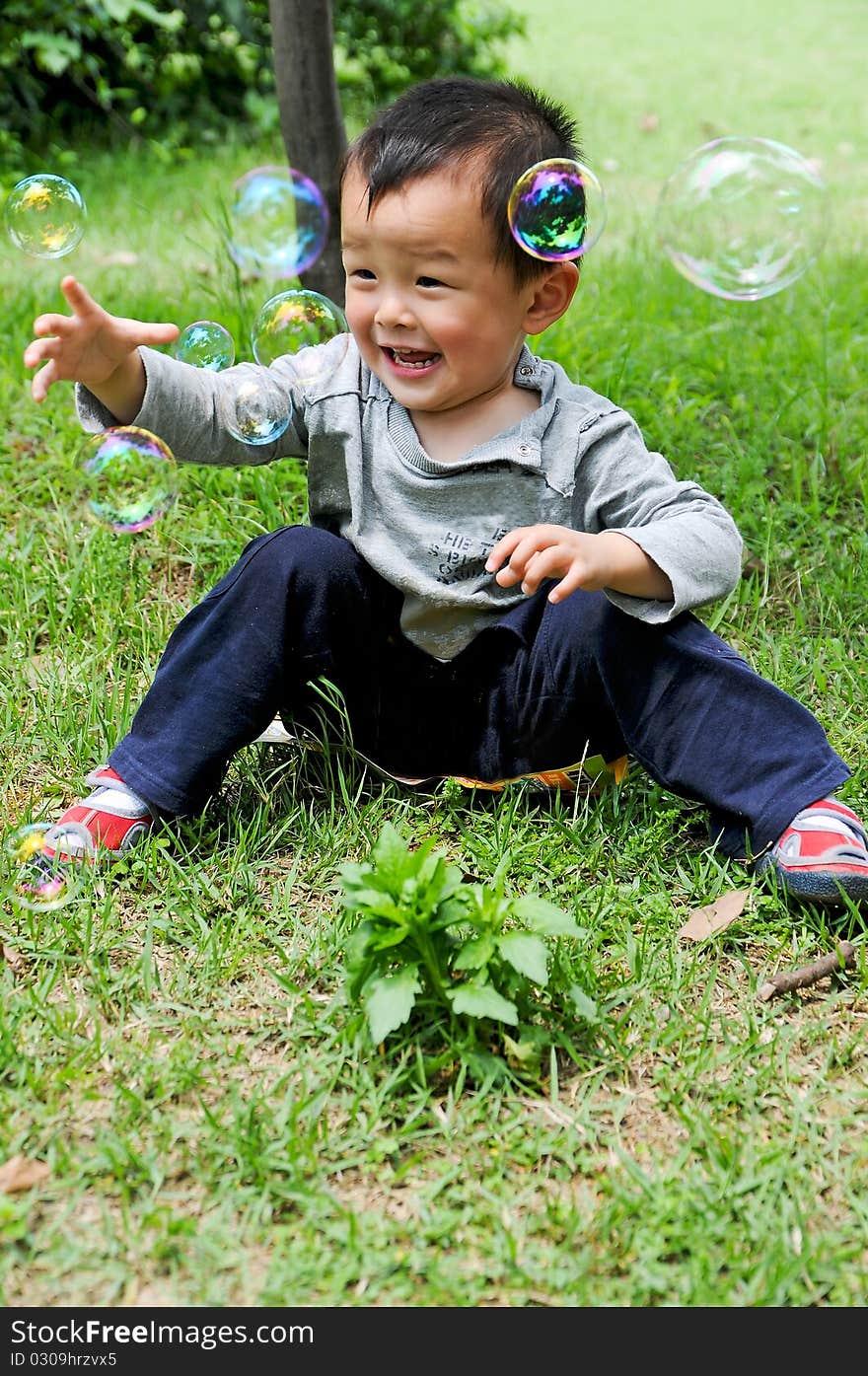 Asian boy playing with soap bubbles.