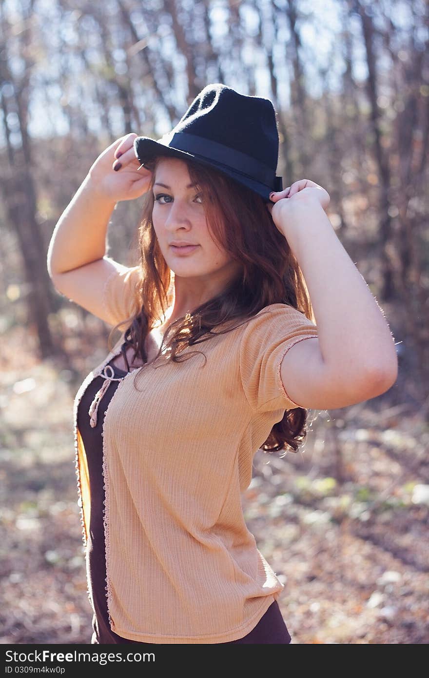 Portrait of a girl in an elegant hat on a background of autumn forest. Portrait of a girl in an elegant hat on a background of autumn forest