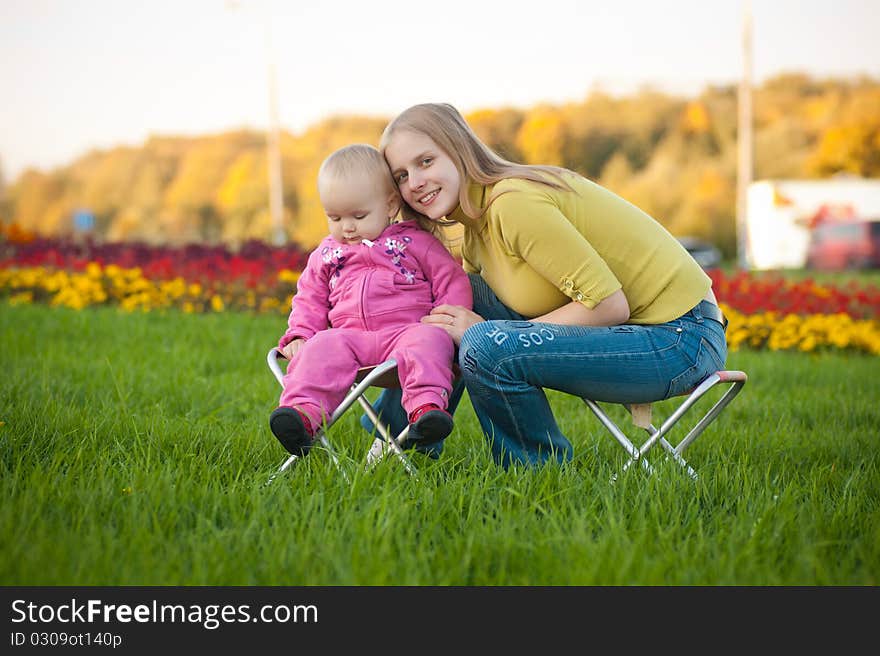 Woman And Cute Baby Sitting On Chairs In Park