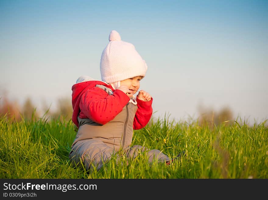 Young adorable baby sit on top of hill and taste grass