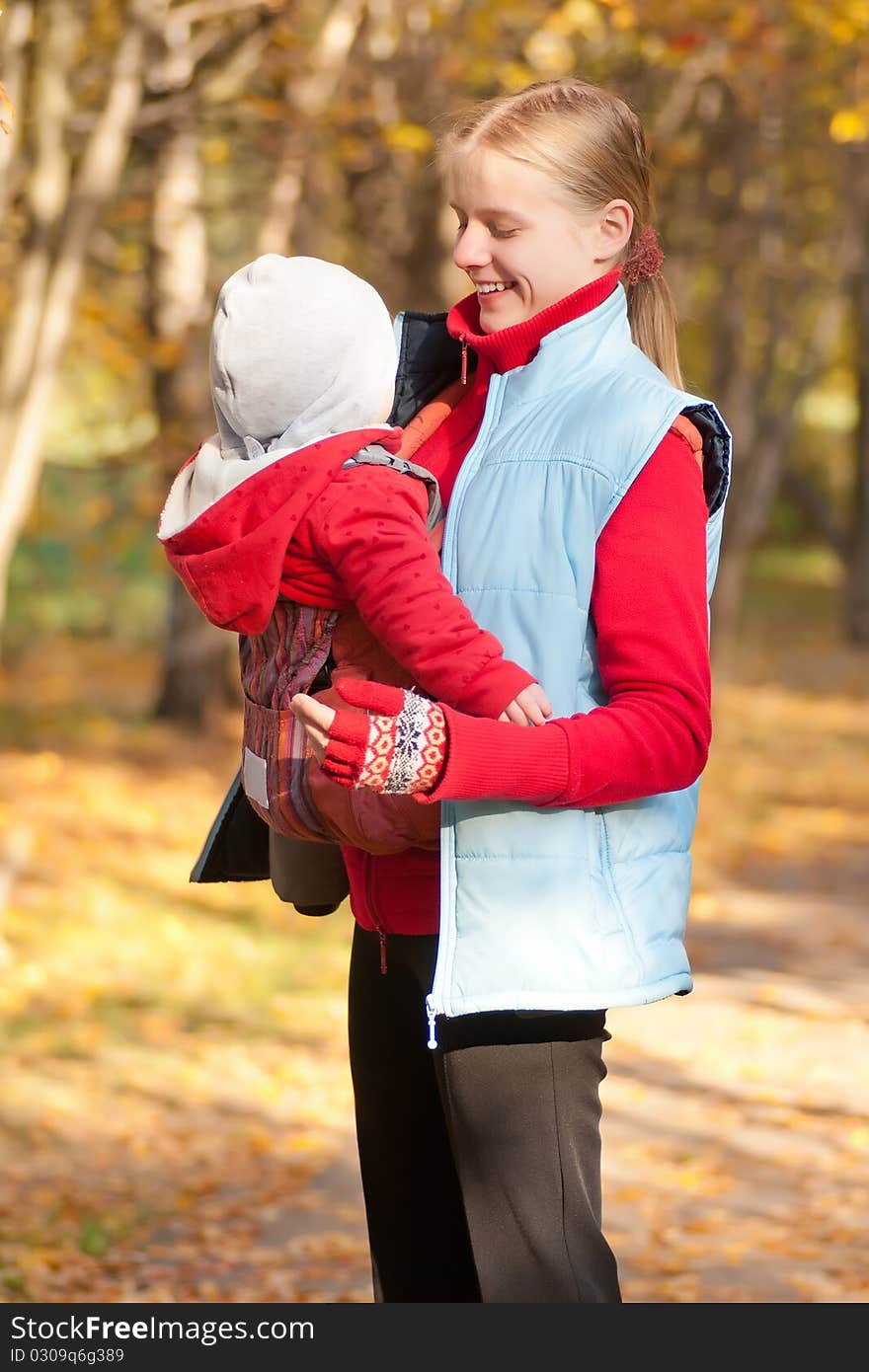 Young adorable mother carry toddler baby in park