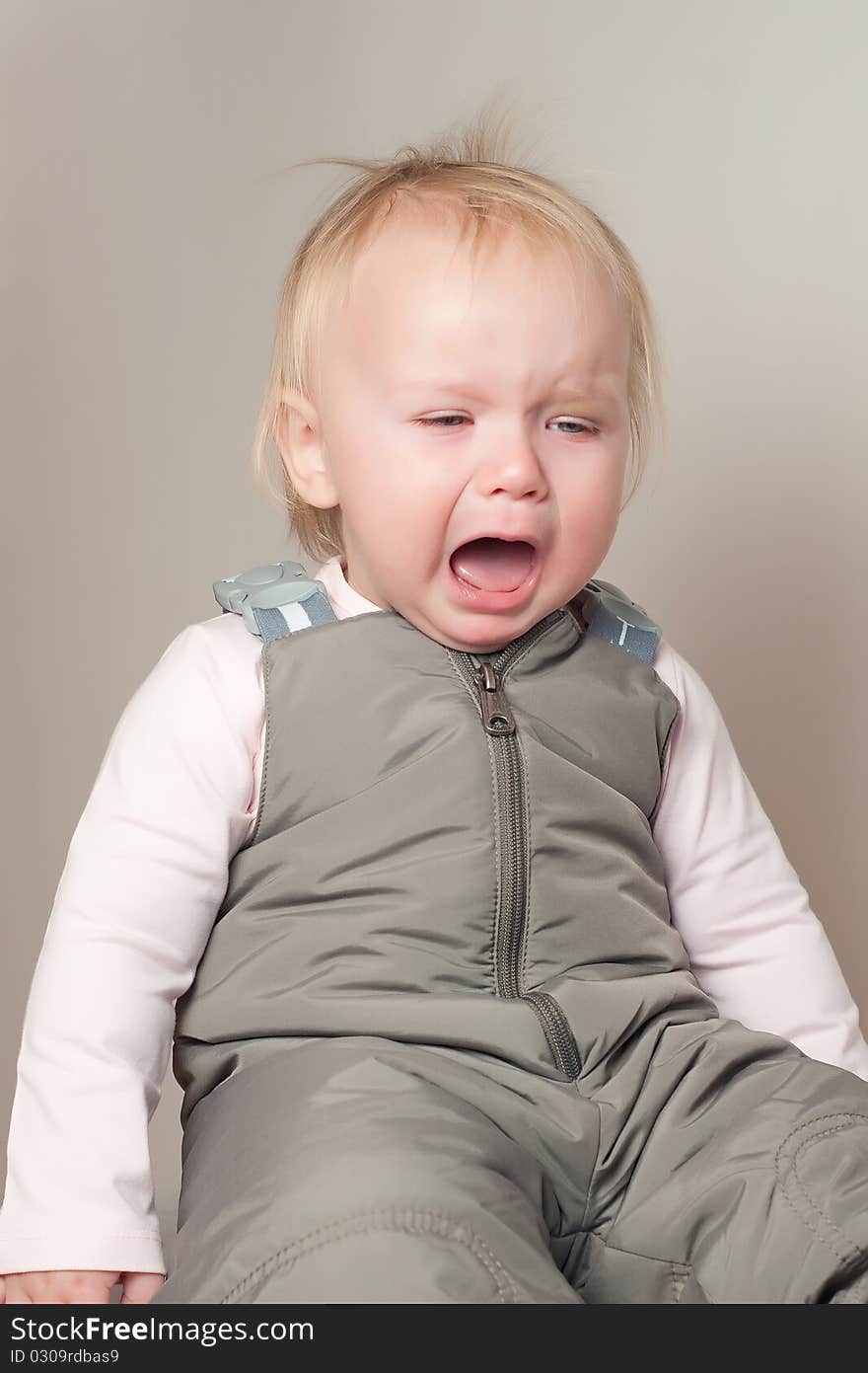 Portrait of crying young baby sit on chair