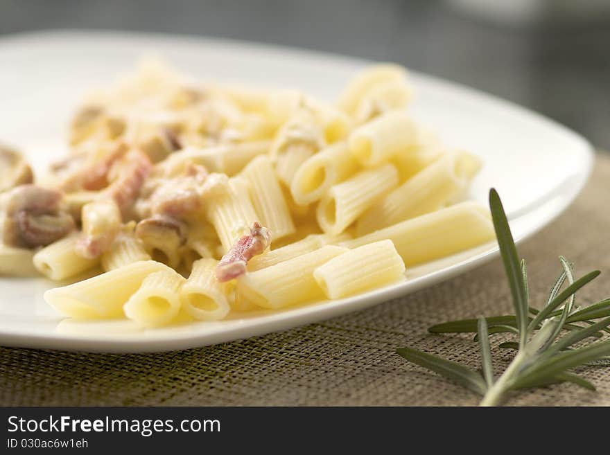 A plate of macaronis with carbonara sauce and bacon. A plate of macaronis with carbonara sauce and bacon