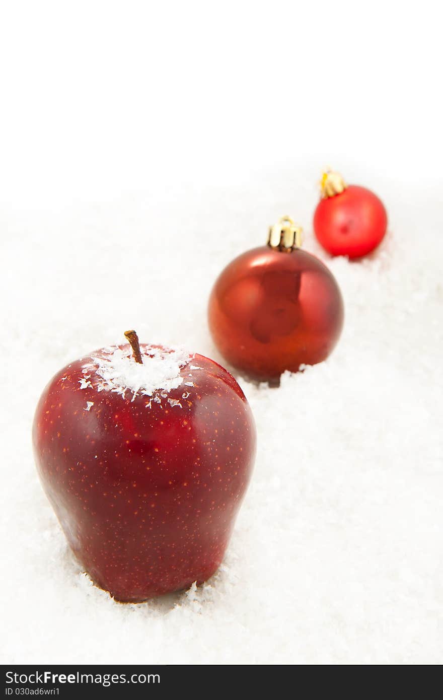 Fresh red apple and red christmas balls on the white snow. Fresh red apple and red christmas balls on the white snow