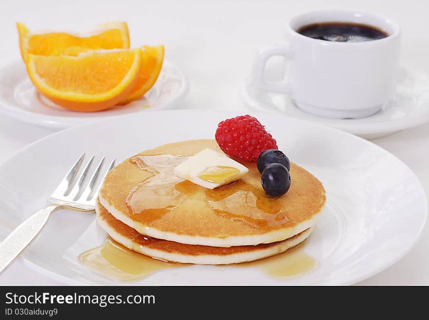 Light and fluffy buttermilk pancakes smothered in maple syrup garnished with a pat of butter and summer berries. Light and fluffy buttermilk pancakes smothered in maple syrup garnished with a pat of butter and summer berries