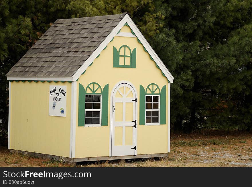 A small pretty little building representing a house buit for Habtat For Humanity, with a sign asking people to save cans to help raise money for the projects. A small pretty little building representing a house buit for Habtat For Humanity, with a sign asking people to save cans to help raise money for the projects.