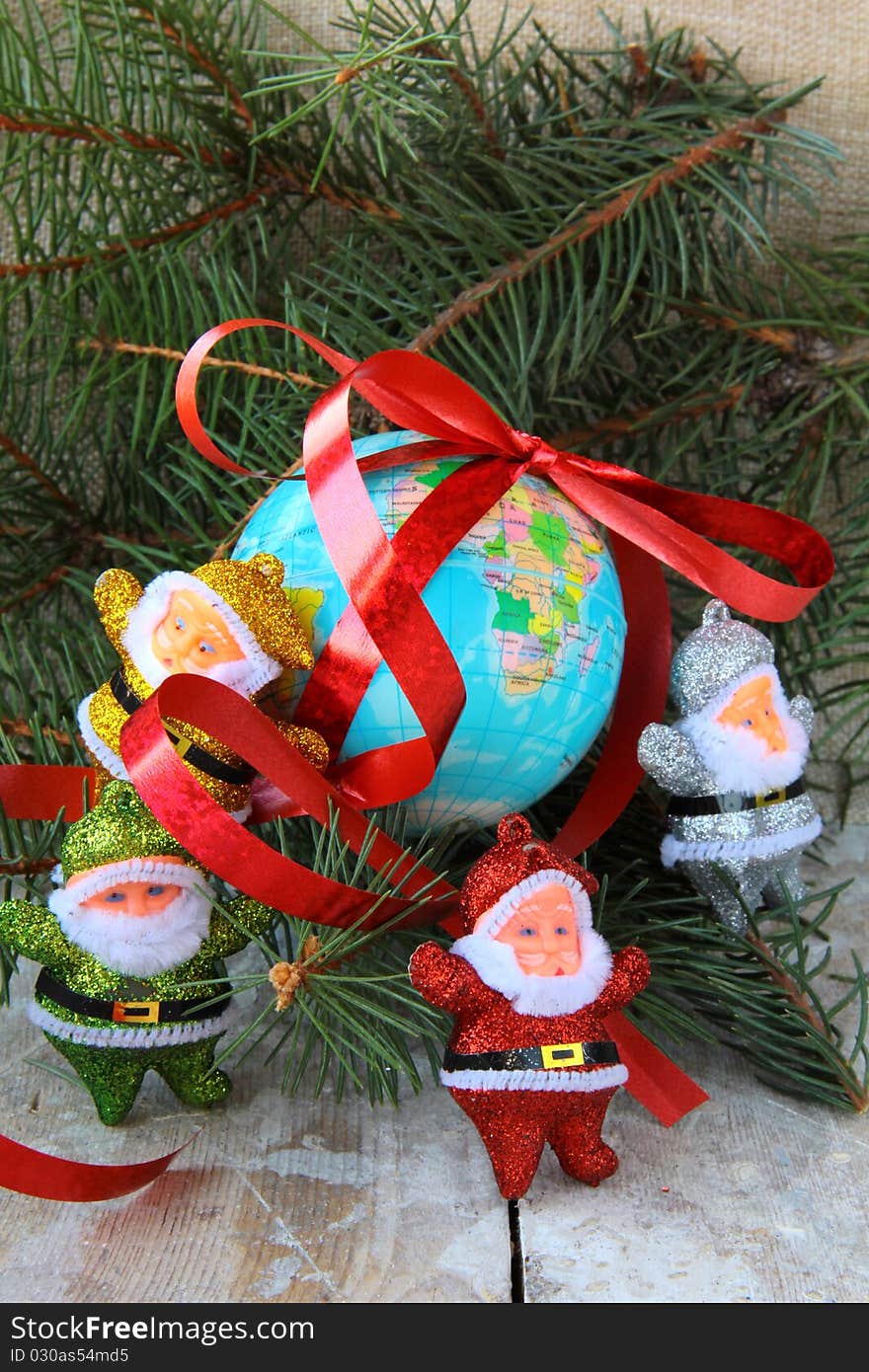 Globe with a gift ribbon and lots of Santa Clauses around. Globe with a gift ribbon and lots of Santa Clauses around