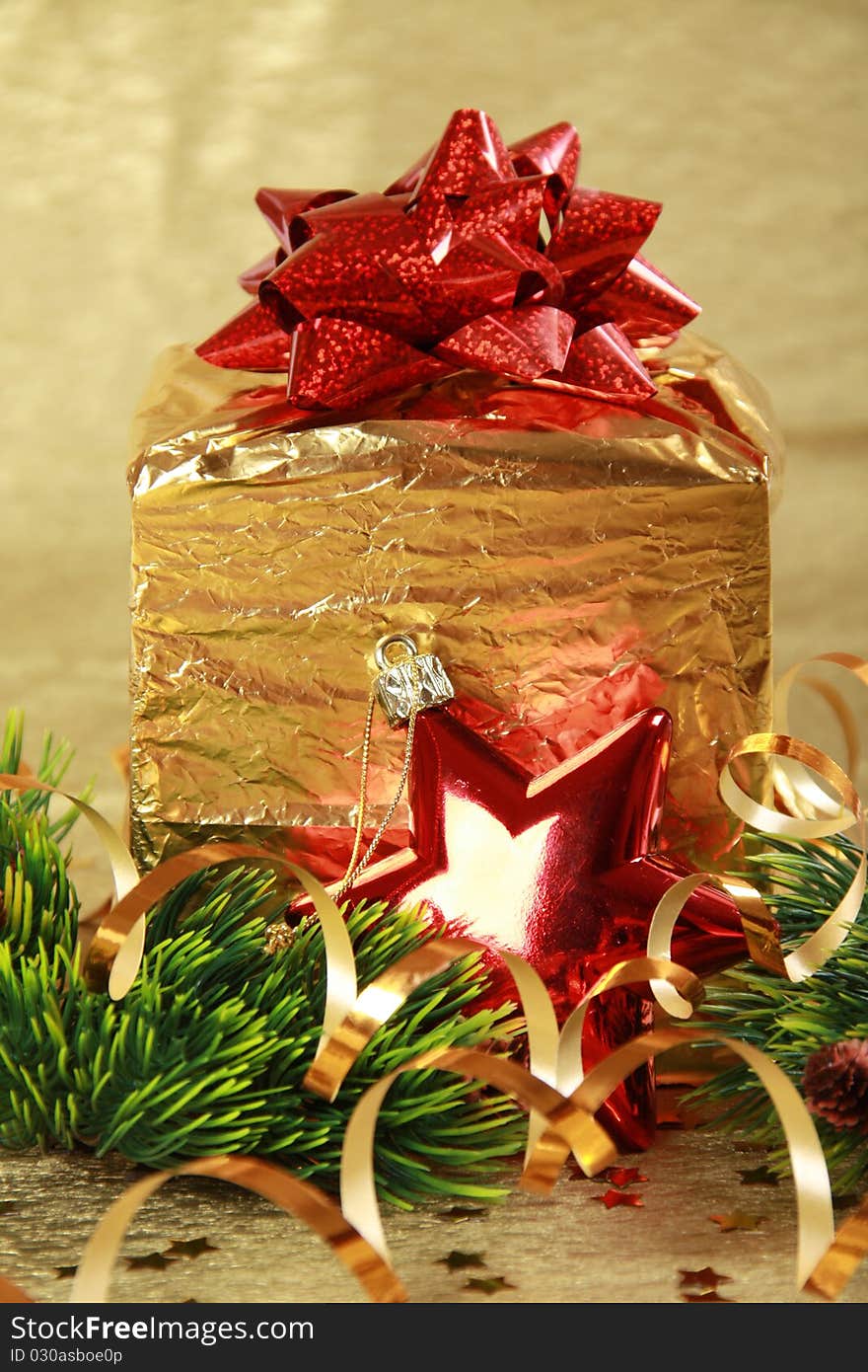 Golden christmas gift box with red bow and star
