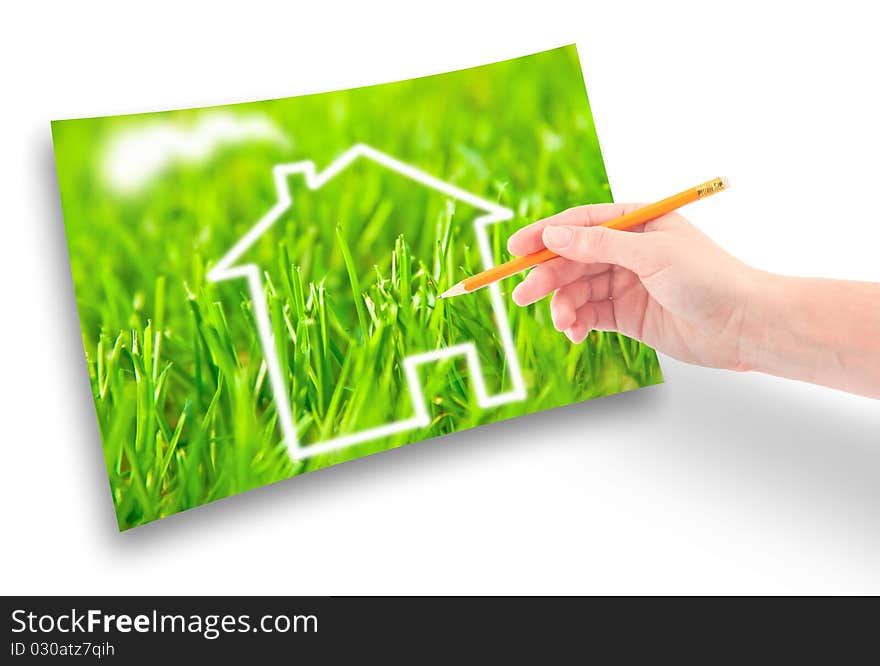 Hand of a girl with a pencil draws a house against on the green grass. Hand of a girl with a pencil draws a house against on the green grass.